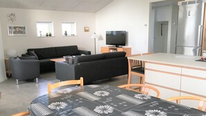 Un salon moderne comprenant un canapé, un téléviseur et un coin repas avec une table.