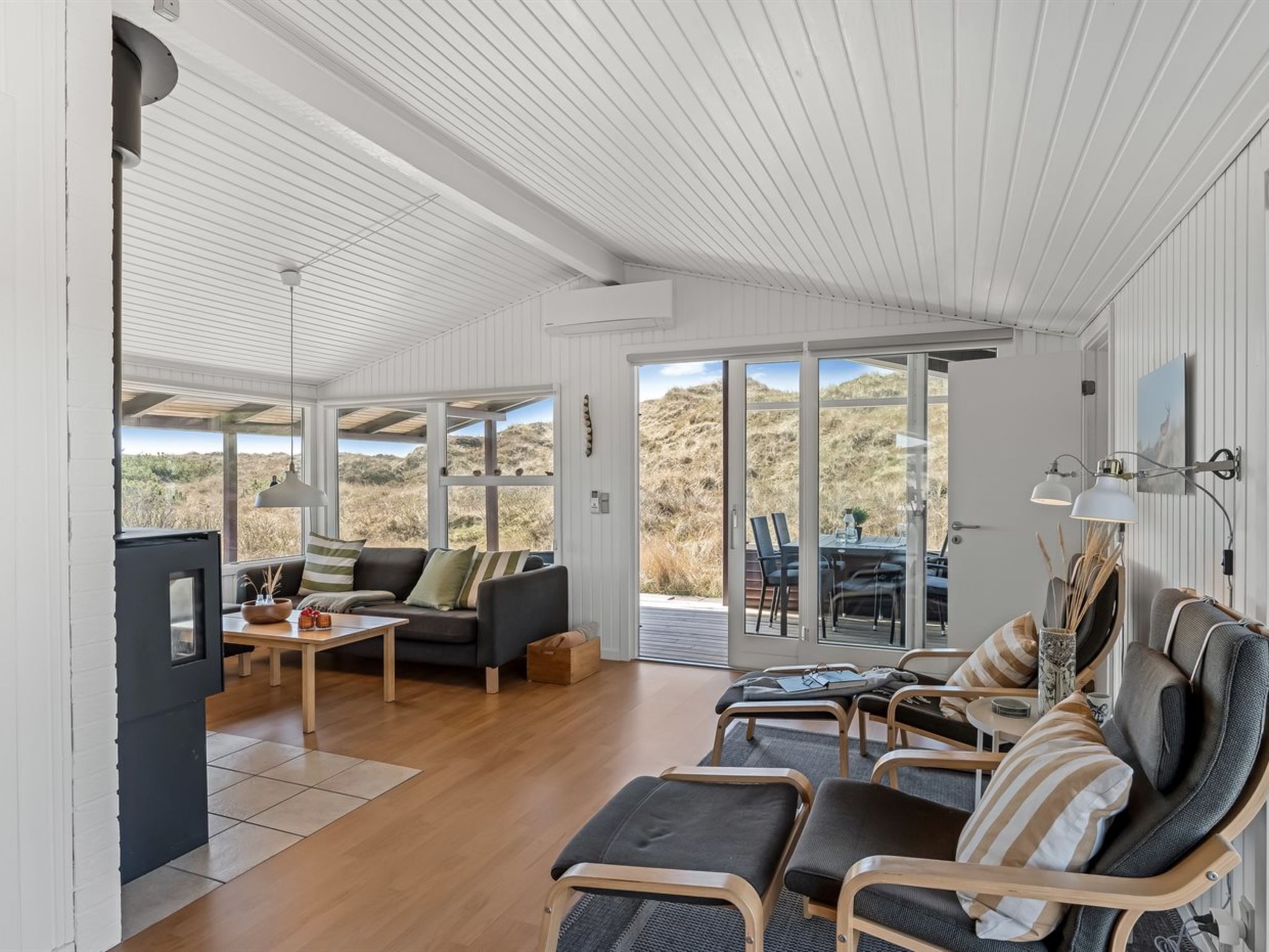 A spacious living area with a large window, a sofa, a coffee table, and a dining table with chairs.