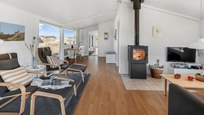 A modern interior with a wood-burning stove, a TV, and a dining area.