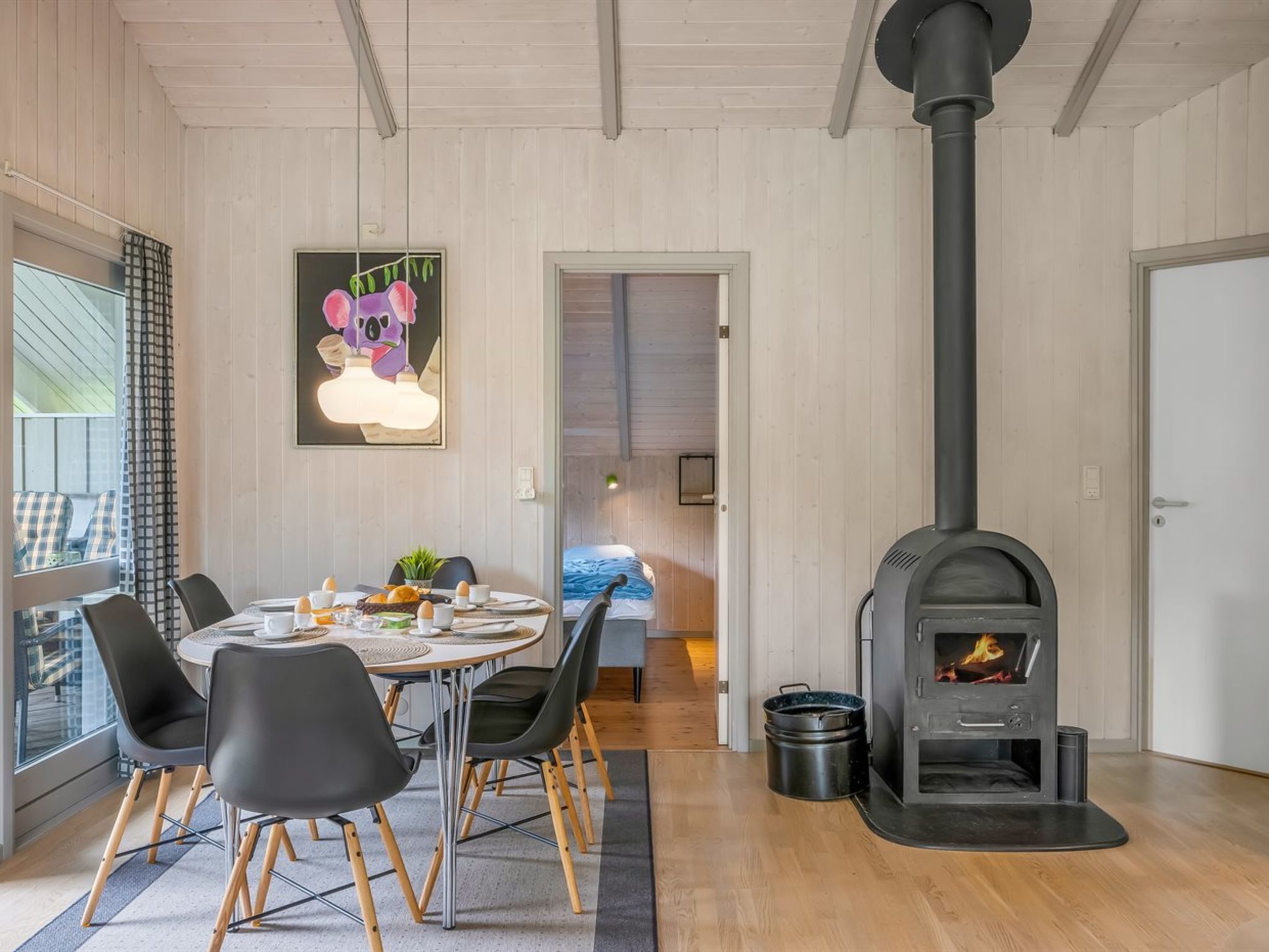 A dining area with a round table, chairs, a fireplace, and a window with curtains.