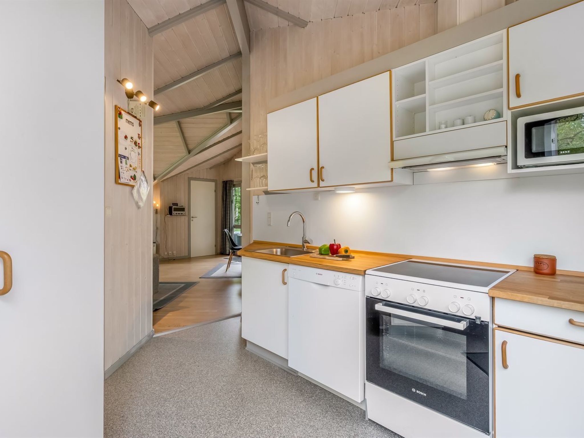 A modern kitchen with white cabinets, a Bosch oven, and a microwave.