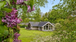 Une maison de plain-pied avec un toit en pente, un porche à l’avant et une pelouse bien entretenue.