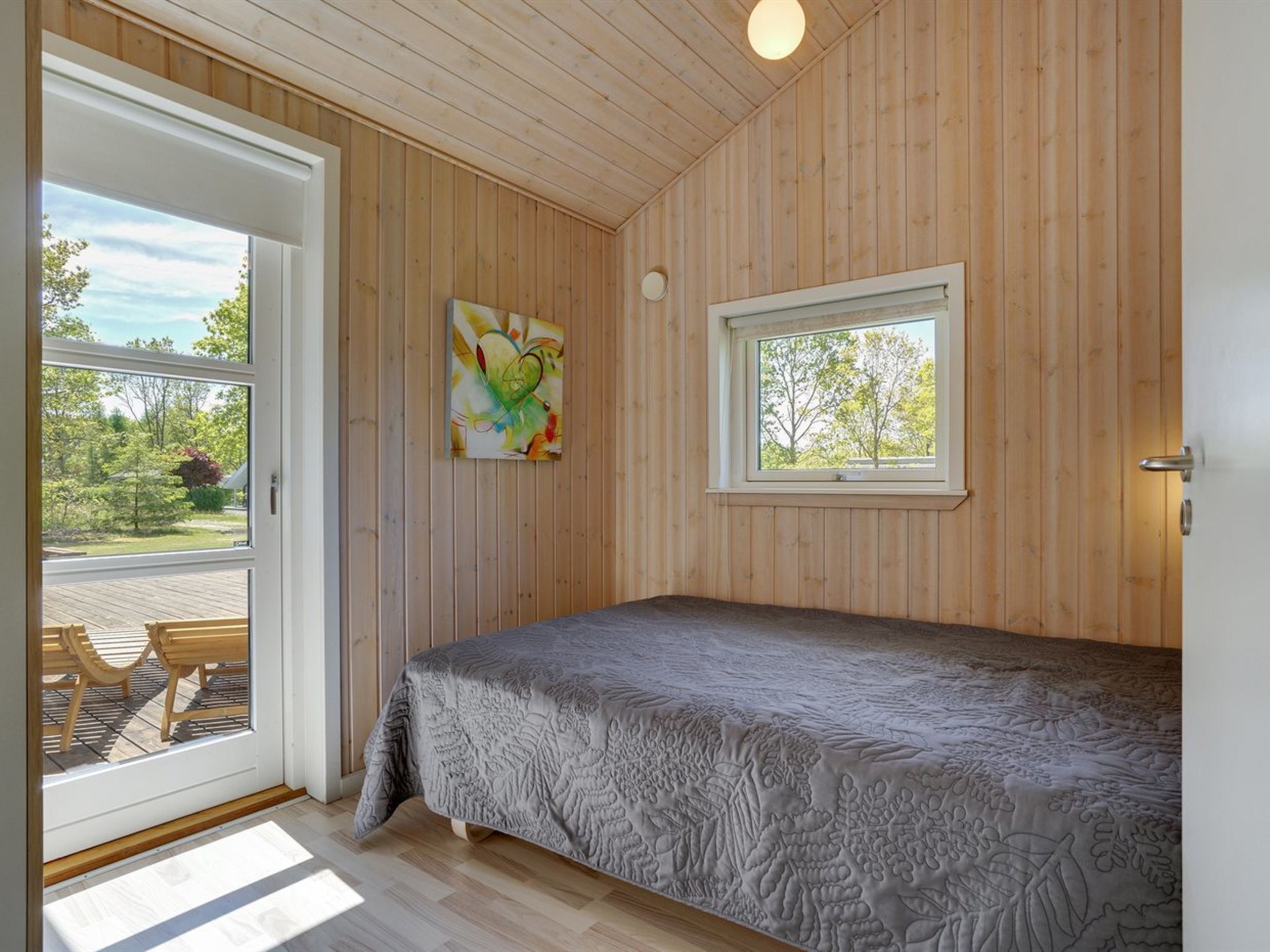 Un dormitorio con cama, ventana y puerta que da a un espacio al aire libre.