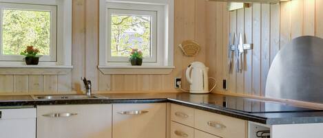 A modern kitchen with wooden cabinets, a stainless steel sink, and a kettle on the counter.