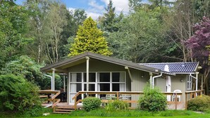 A single-story building with a flat roof, large windows, and a covered porch with a wooden railing.