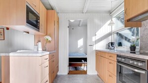 A compact kitchen with wooden cabinets, a built-in oven, and a window providing natural light.