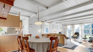 A spacious dining area with a round table, wooden chairs, and a central light fixture.