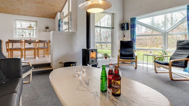 Una sala de estar acogedora con chimenea, un comedor y ventanas amplias.
