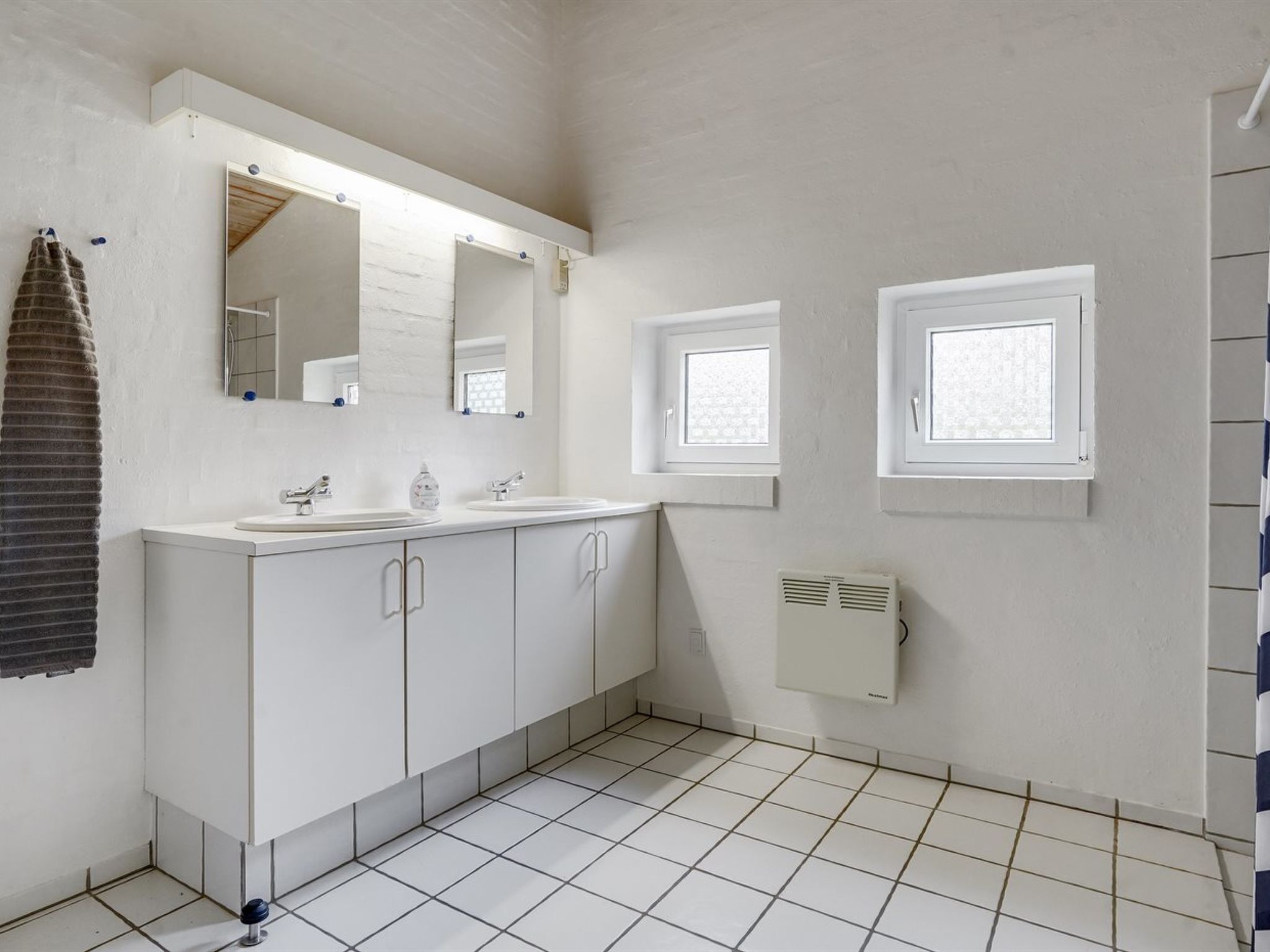A bathroom with two sinks, a large mirror, and a window.