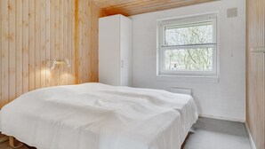 Un dormitorio con cama, ventana y paredes de madera.