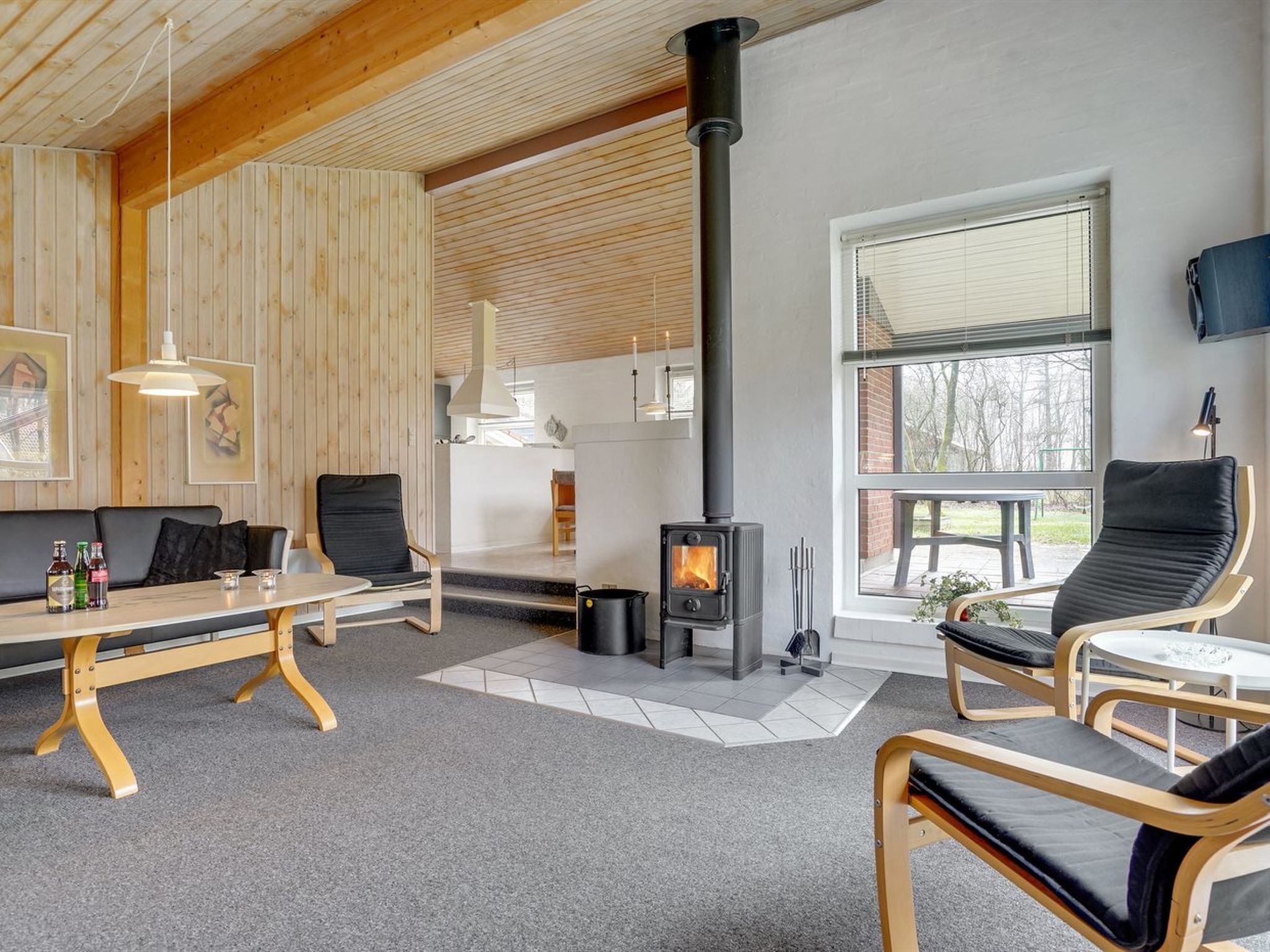 A cozy room with a fireplace, wooden walls, a sofa, and a dining table.