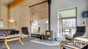 Una habitación acogedora con chimenea, paredes de madera, un sofá y una mesa de comedor.