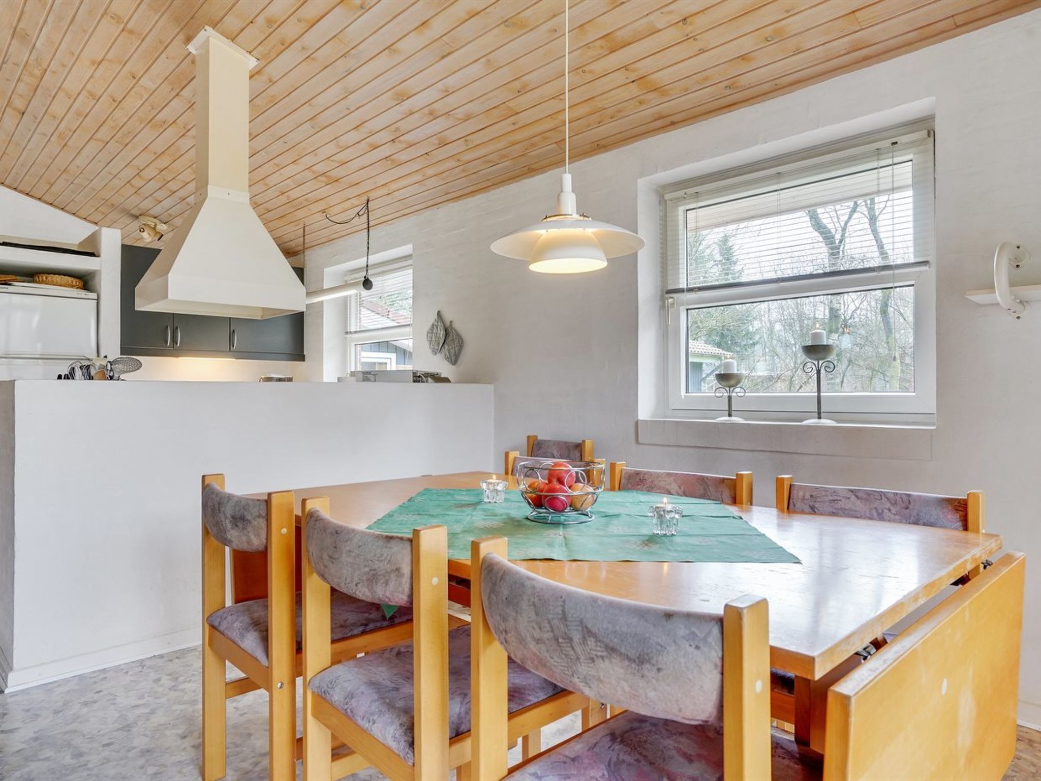 A modern kitchen with wooden cabinets, a central island, and a dining area with a table and chairs.