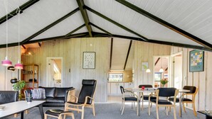 A cozy interior with a wooden ceiling, a living area with a sofa and chairs, a dining table, and a kitchen in the background. - "Joona" - 600m from the sea by Interhome (Sydals)