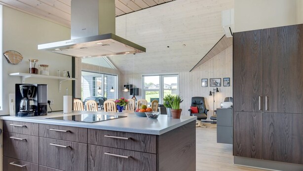 Una cocina moderna con una isla grande, armarios de madera y una estufa empotrada.