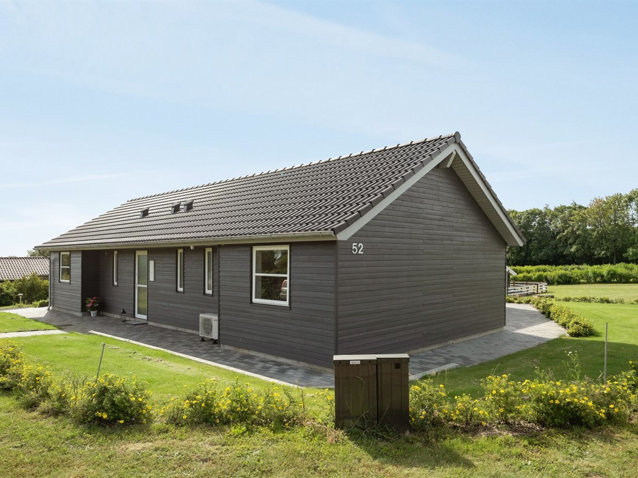 A single-story building with a grey exterior, a tiled roof, and a number '52' on the side.