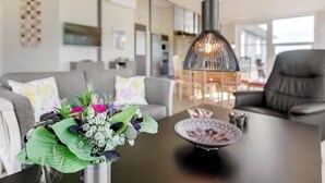 Una sala de estar moderna con un sofá gris, una mesa de centro con un plato decorativo y una lámpara colgante.
