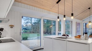 A modern kitchen with white cabinetry, a large island, and a view of a backyard.