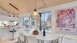 A modern kitchen with white cabinets, a marble countertop, and pendant lighting.