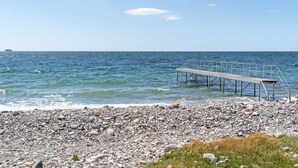 A rocky beach with a wooden pier extending into the sea.