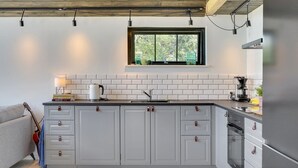 A modern kitchen with grey cabinets, a window, and a built-in oven.