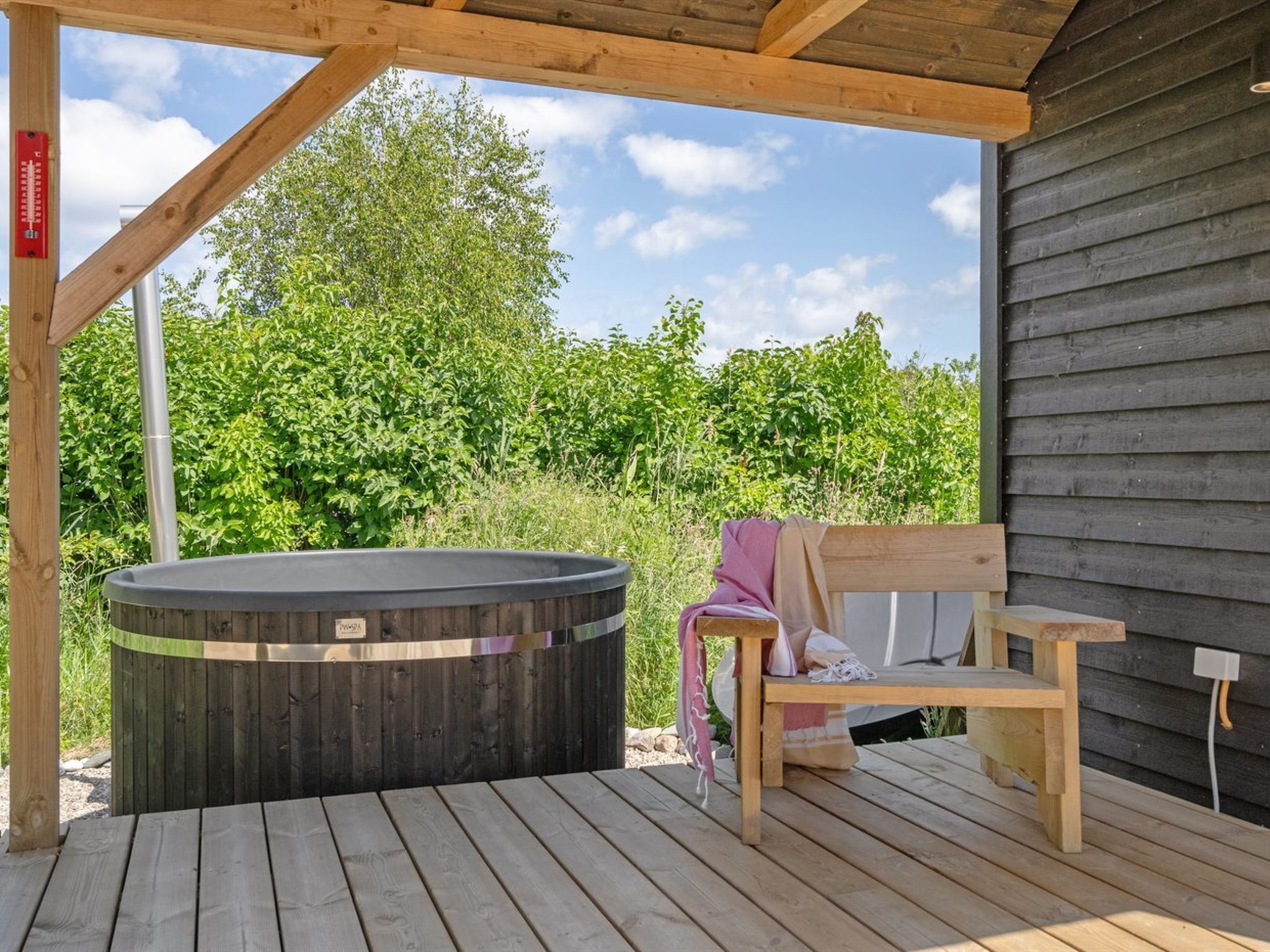 Eine Holzterrasse mit Whirlpool und Bank.