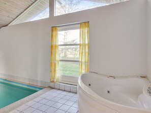 Une salle de bain avec une grande baignoire, une fenêtre avec des rideaux jaunes et une piscine.