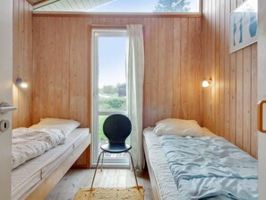 Un petit logement composé d’une seule pièce, comprenant deux lits, une chaise, une fenêtre et une porte.