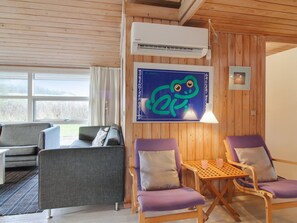 Une pièce comprenant un canapé, deux fauteuils, une table, un appareil de climatisation et une œuvre d’art accrochée au mur.