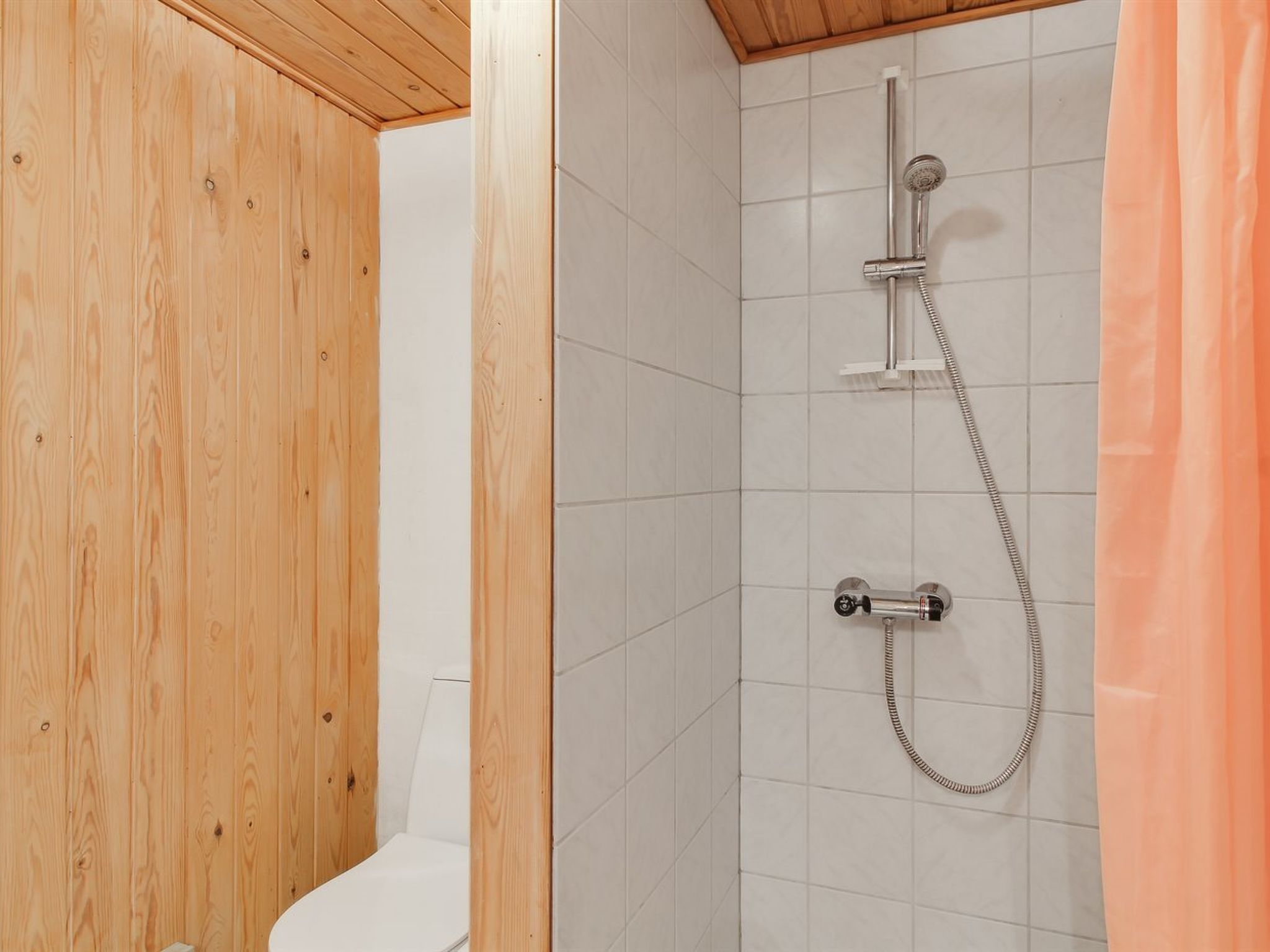 Une salle de bain avec une douche, des toilettes et des murs en bois.