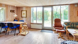 A wooden-paneled room with a dining table, chairs, a sofa, and a rocking chair. - "Jaane" - 650m to the fjord by Interhome (Hemmet)