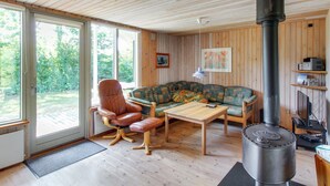A cozy living room with a wooden ceiling, a large window, a sofa, a chair, a table, and a wood-burning stove. - "Jaane" - 650m to the fjord by Interhome (Hemmet)