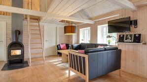 A cozy living room with a fireplace, a sofa, a TV, and a wooden floor.