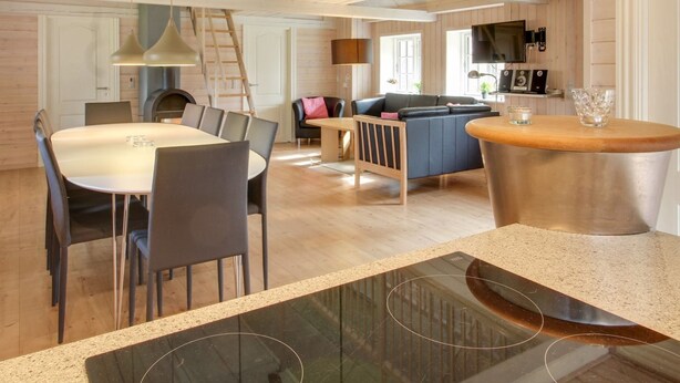 A spacious living area with a high ceiling, a dining table, a sofa, and a kitchen area with a TV.