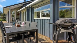 A modern outdoor dining area with a wooden deck, a table with chairs, and a barbecue grill. - "Villads" - 1km from the sea by Interhome (Løkken)