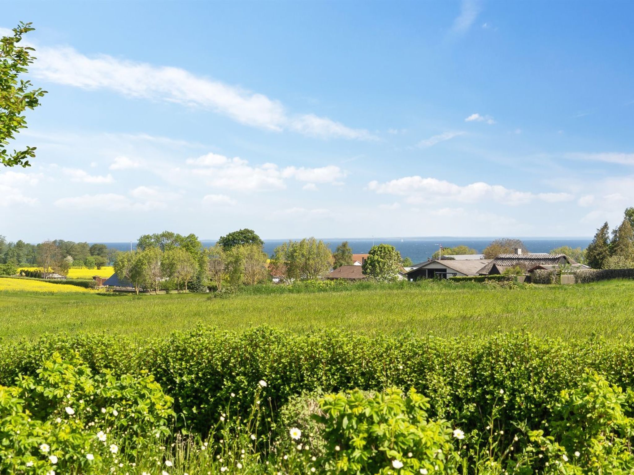 Ländliche Landschaft mit Feldern, einigen Häusern und Blick aufs Meer.