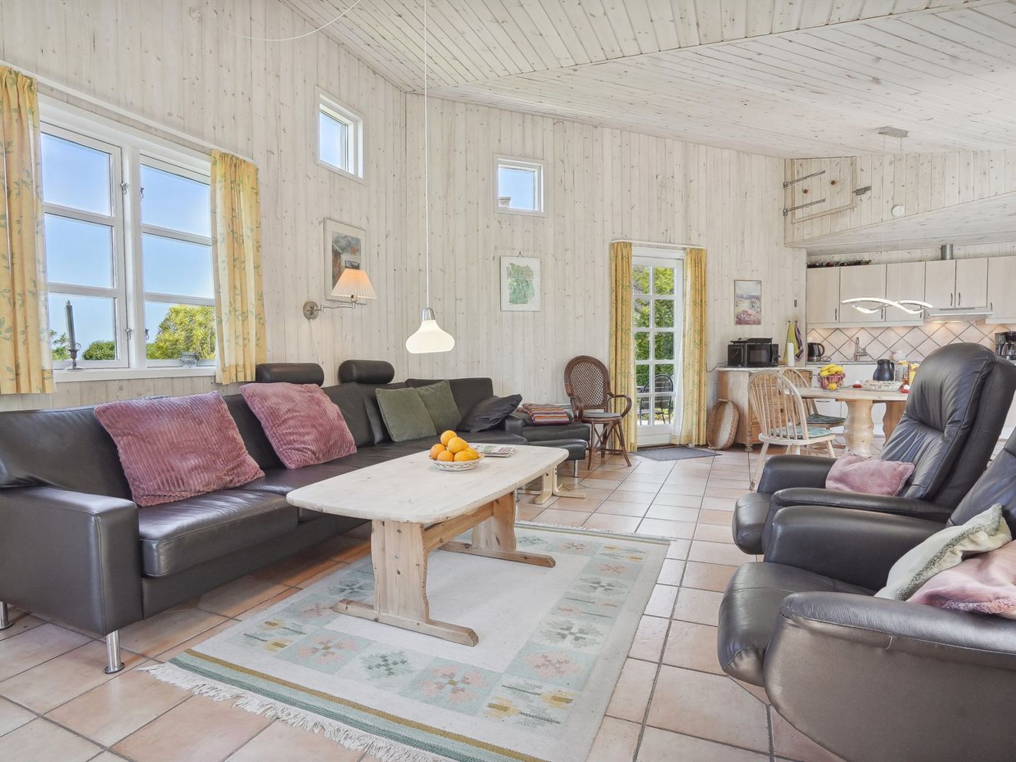 A spacious living room with a sofa, armchairs, a coffee table, and a dining area.