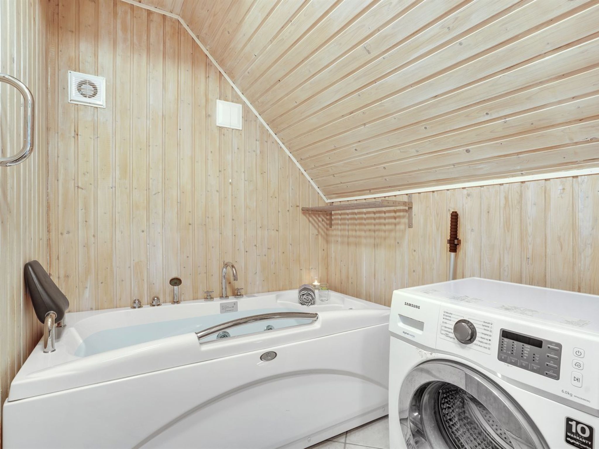Eine Holzhütte mit einer weißen Badewanne und einer Samsung Waschmaschine.