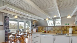 A modern kitchen with wooden flooring, white cabinetry, and a large window. - "Alleta" - 600m from the sea by Interhome (Ringkøbing)