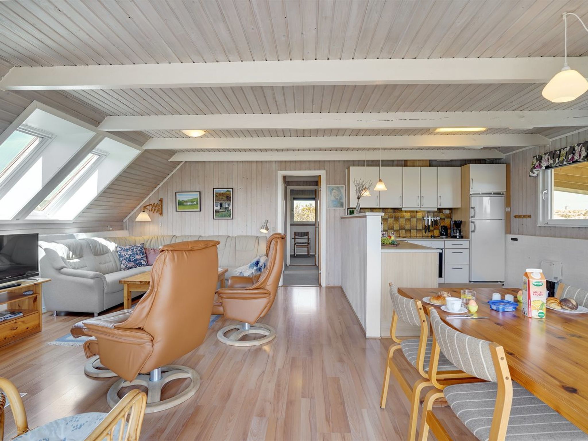 A modern interior with a dining area, kitchen, and seating with a view of the outdoors.