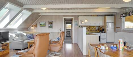 A modern interior with a dining area, kitchen, and seating with a view of the outdoors.