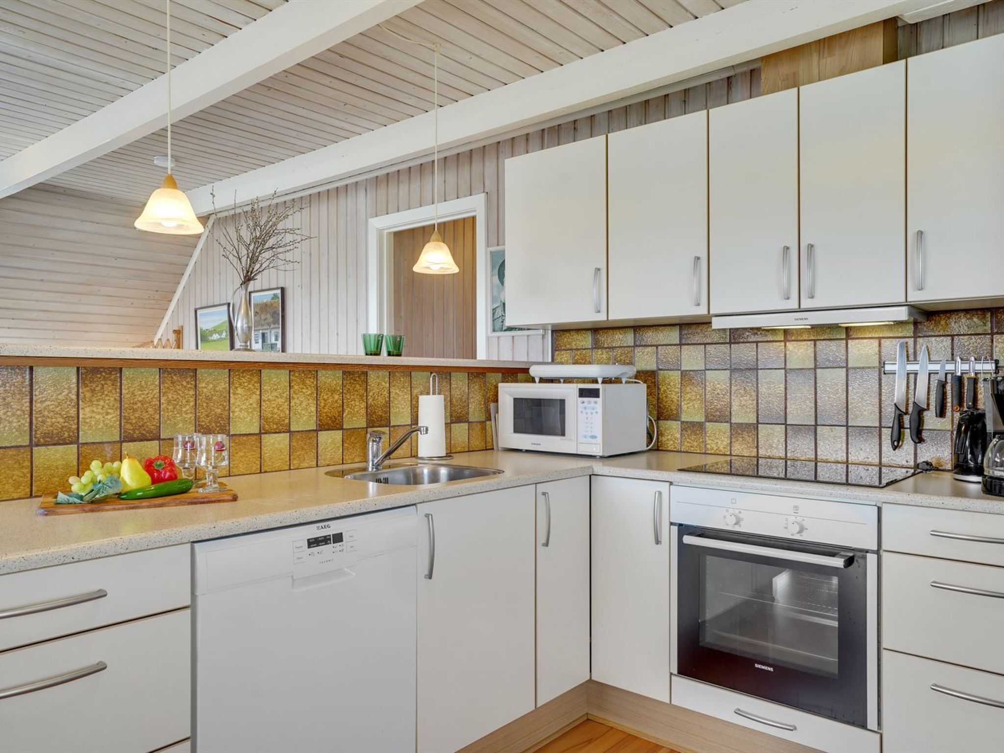 Eine moderne Küche mit weißen Schränken, einem Geschirrspüler, einer Mikrowelle und einem Backofen.