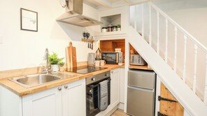 A modern kitchen with white cabinets, stainless steel appliances, and a wooden countertop. - Bwthyn Lili (Cemaes Bay)