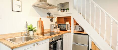 A modern kitchen with white cabinets, stainless steel appliances, and a wooden countertop.