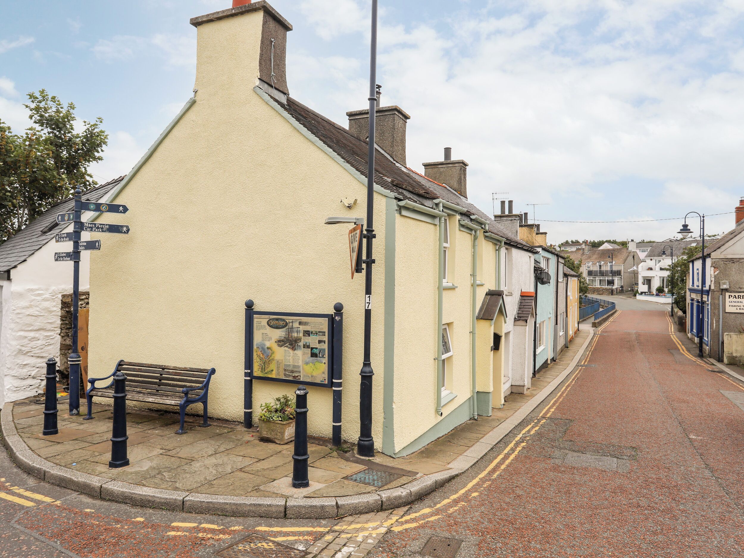 A narrow street with a bench and a directional signpost.
