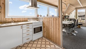 Una cocina moderna con un gran ventanal, techo de madera y comedor con mesa y sillas.