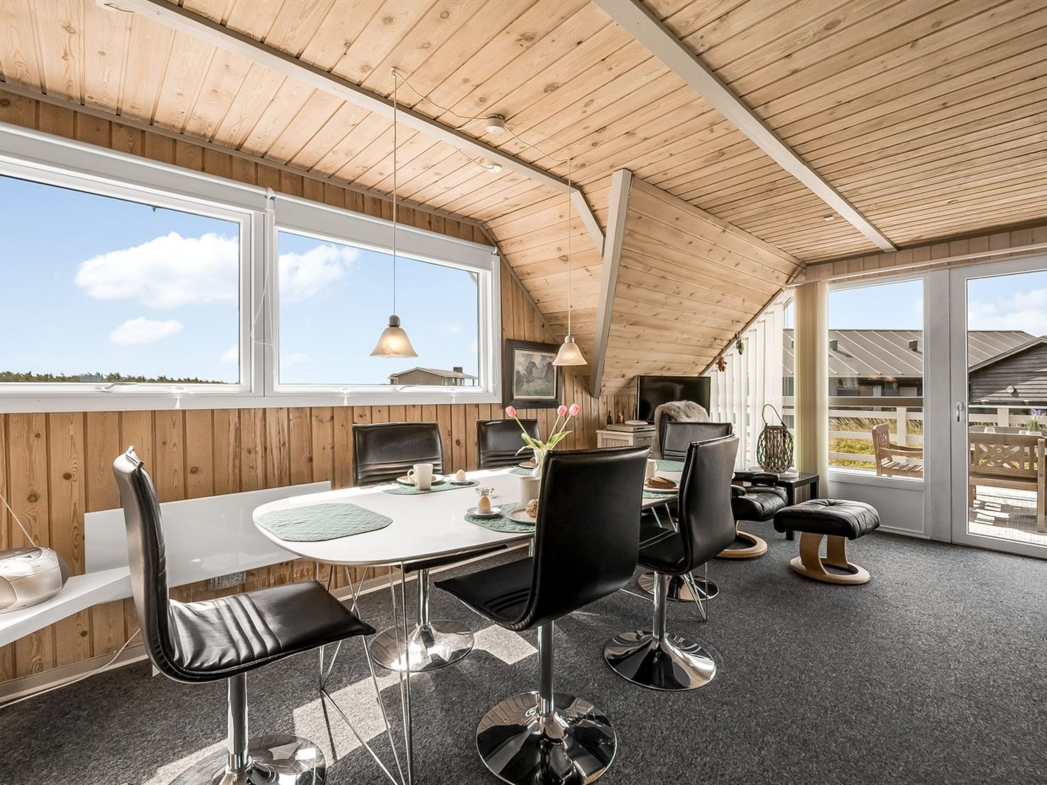 Un espace de restauration moderne avec un plafond en bois, de grandes fenêtres et une vue sur le paysage.