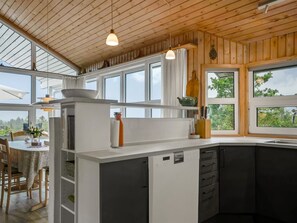 Une cuisine moderne dotée d’un grand îlot central, d’un plafond en bois et de grandes fenêtres.