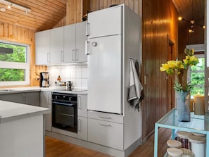 A modern kitchen with white cabinets, a built-in oven, and a refrigerator.