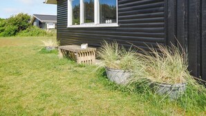 Ein schwarzes Holzhaus mit einem weißen Fenster und einer kleinen Holzbank davor.